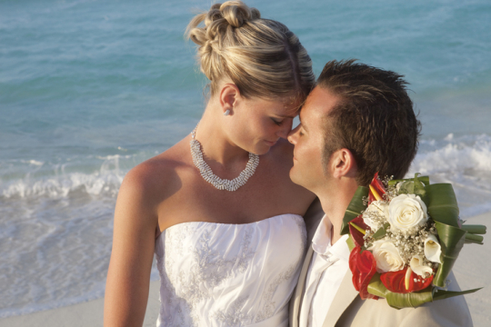 Hochzeitspaar mit Strau&szlig; verliebt am sonnigen Traumstrand