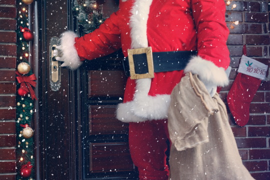 Weihnachtsmann legt Hand auf T&uuml;rklinke, um anzudeuten, dass er das Haus betreten m&ouml;chte